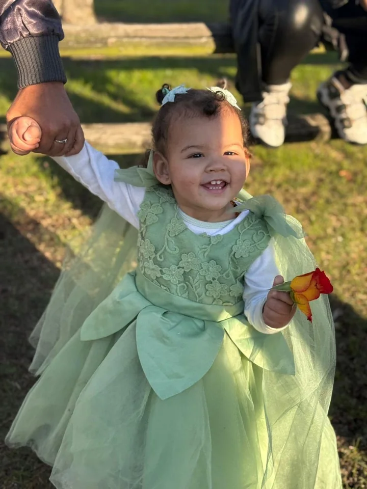 Armani — our warrior princess — smiling in a soft green flower-girl dress, holding a rose